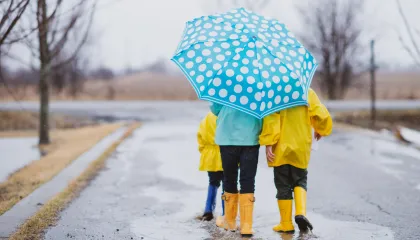 family walking underneath blue polka dotted umbrella