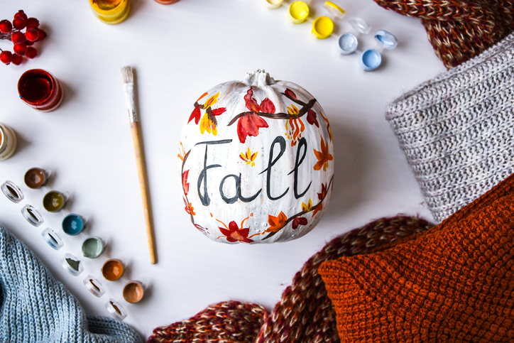 Pumpkin painted with leaves and the word "Fall."