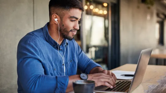 Young man wearing a blue shirt working on a laptop computer
