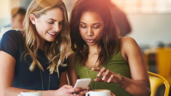 Two women sitting at a table looking at a phone