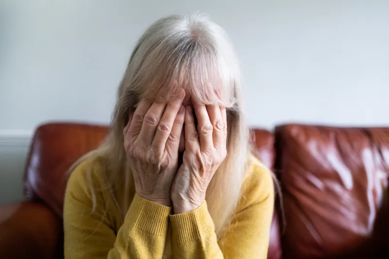 older women with gray hair with her head in her hands