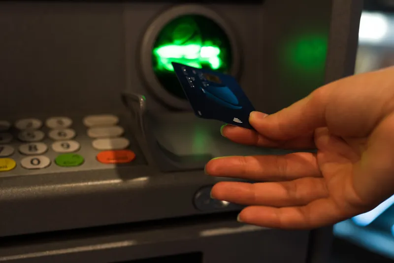 a hand inserting a card into an ATM