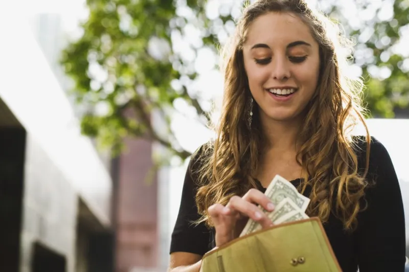 woman pulling money from her wallet smiling