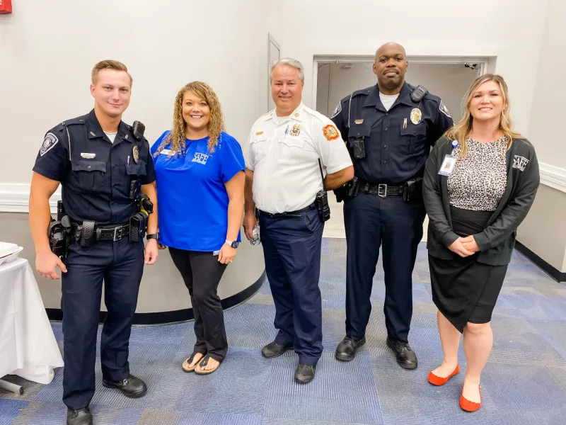 SAFE employees standing and smiling with police officers and fire fighters.