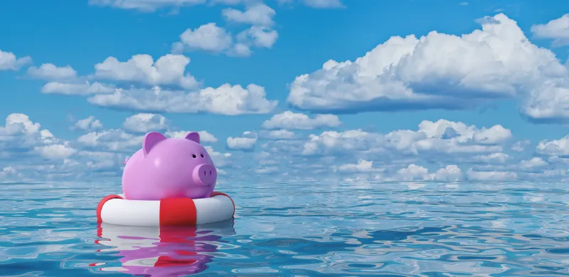 pink piggy bank floating in a red and white innertube in water. 