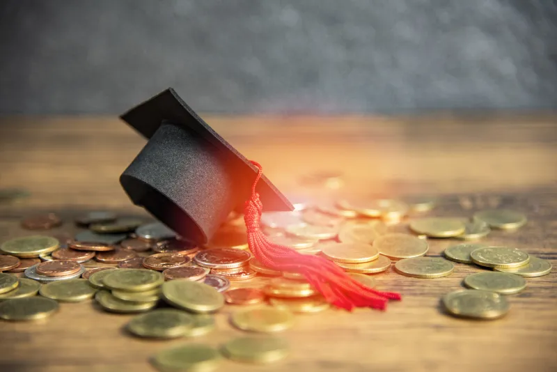 graduation cap sitting on top of a pile of coins