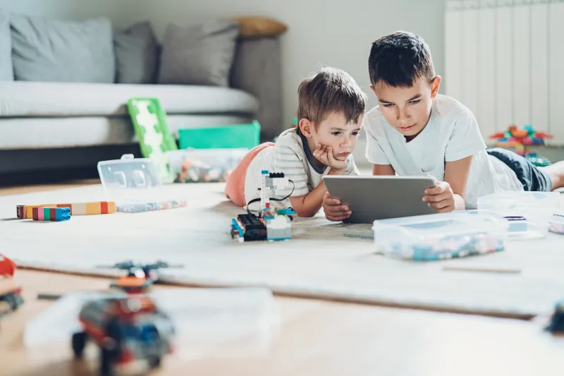 two kids looking on an electronic device