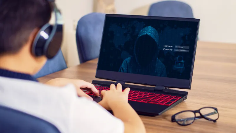 Child on laptop with a dark image of a thief on the screen