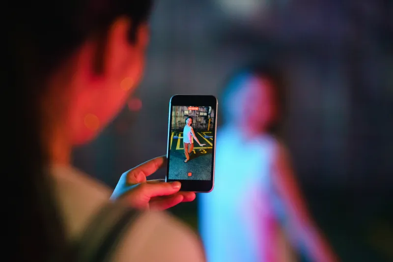 person holding a phone filming another person dancing.