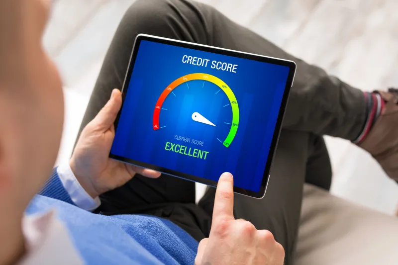 person holding a tablet with a credit score meter on the screen