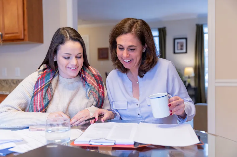 mom and daughter sitting at a table looking at paperwork