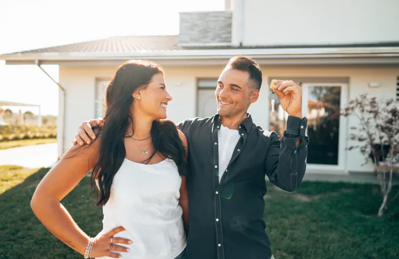 A happy couple holding keys to a home