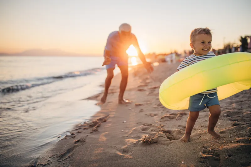 young boy running on the beach with an innertube float