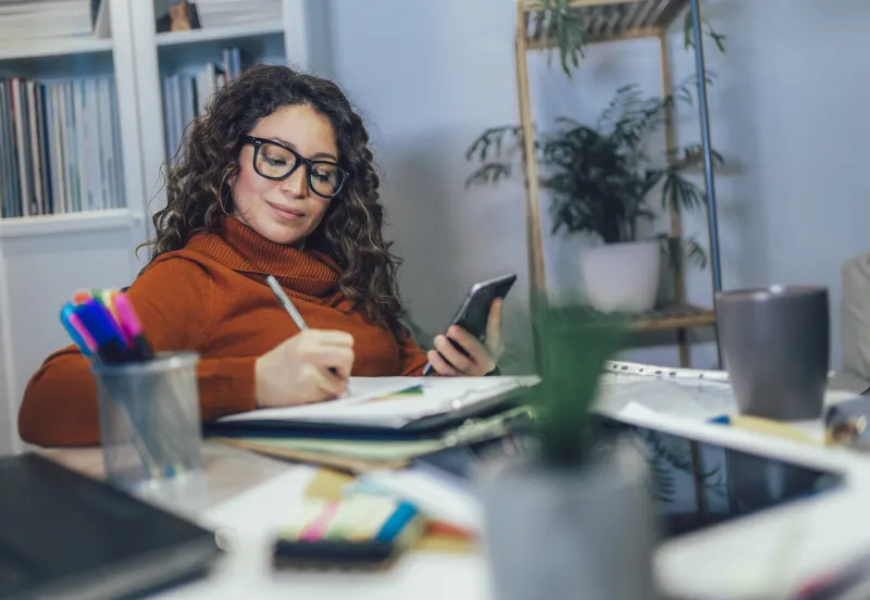 woman wearing glasses writing down her budget.
