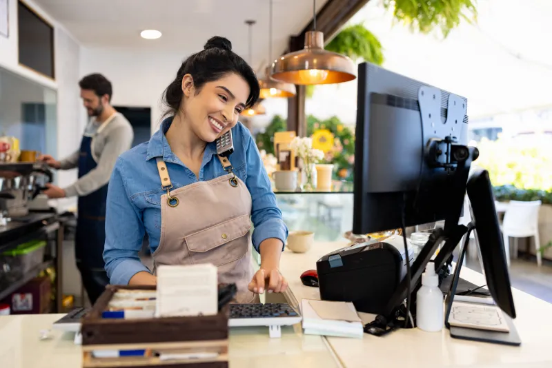 woman on the phone looking at a computer screen smiling