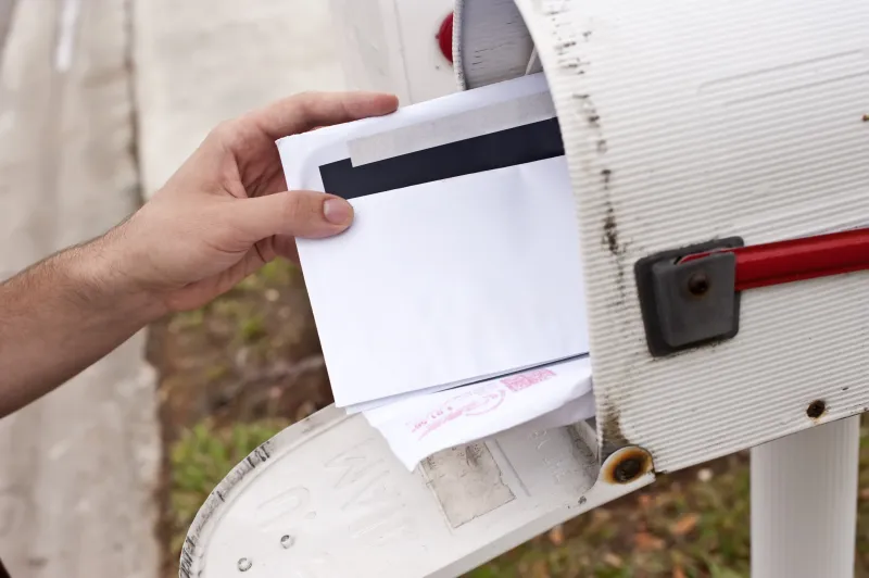 a hand grabbing a letter out of a mailbox