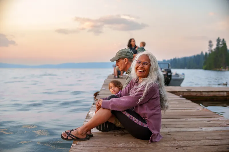 senior woman sitting on a dock by the water with her family