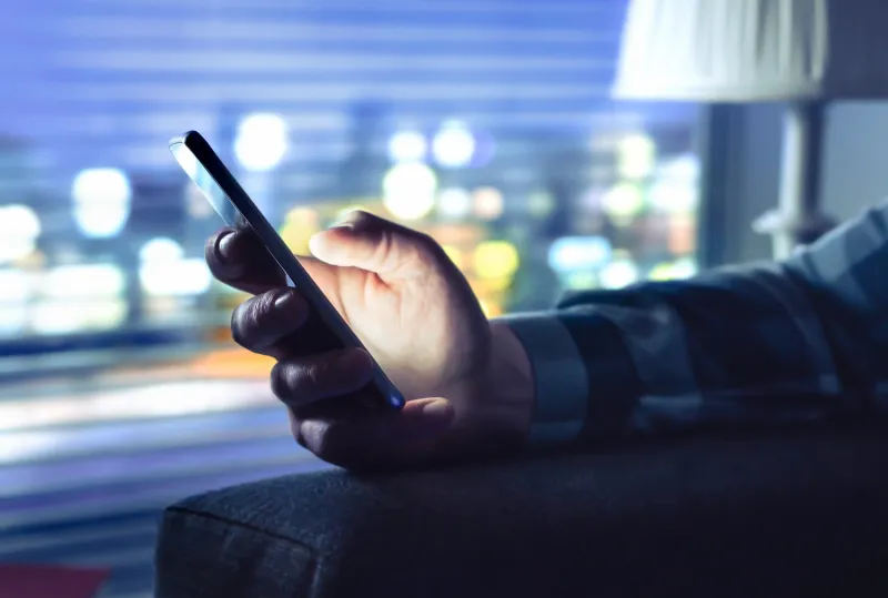 hand holding a smart phone in the shadow