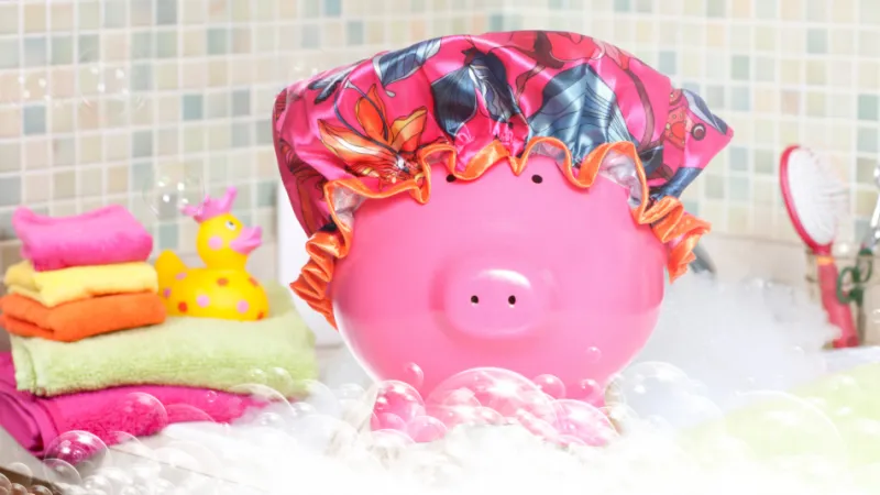 Pink piggy bank wearing a shower cap in a bubble bath