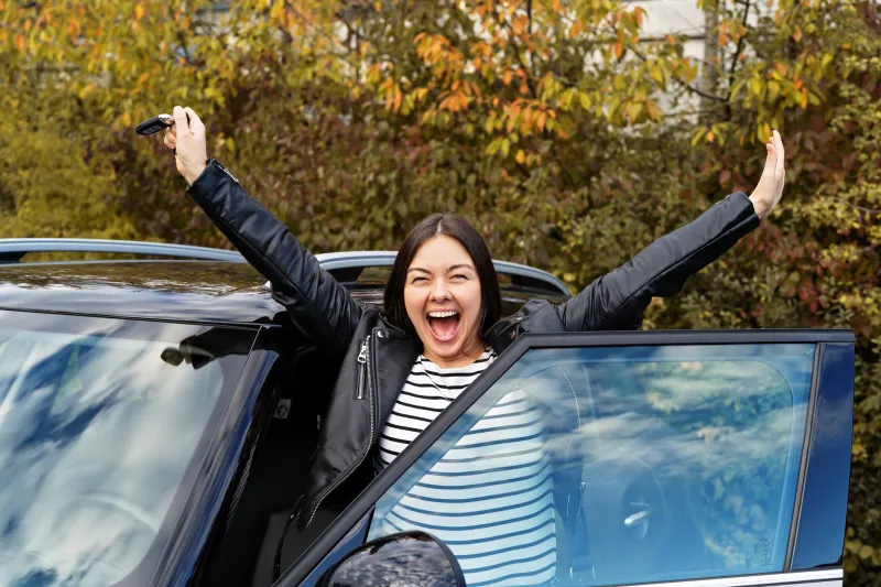 Woman celebrating with new car.