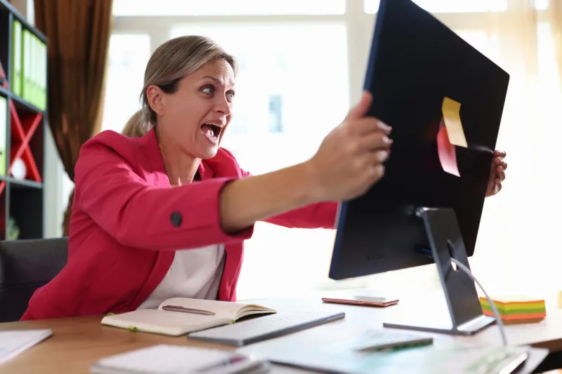 woman wearing pink blazer grabbing a computer monitor