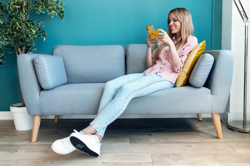 woman sitting on couch holding phone