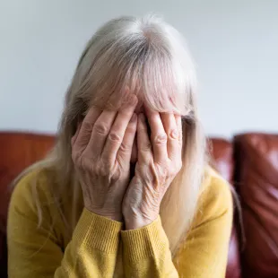 older women with gray hair with her head in her hands