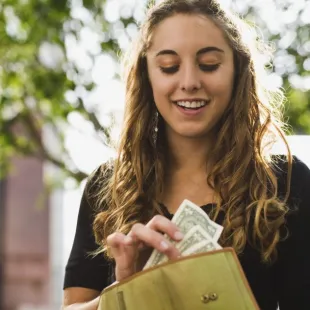 woman pulling money from her wallet smiling