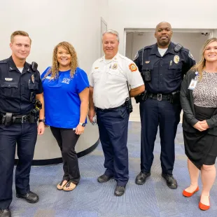 SAFE employees standing and smiling with police officers and fire fighters.