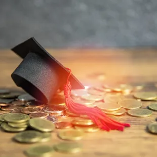 graduation cap sitting on top of a pile of coins