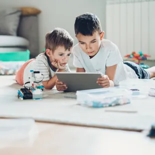 two kids looking on an electronic device