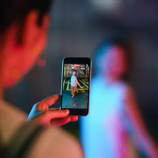 person holding a phone filming another person dancing.
