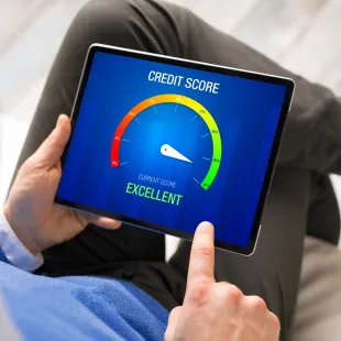 person holding a tablet with a credit score meter on the screen
