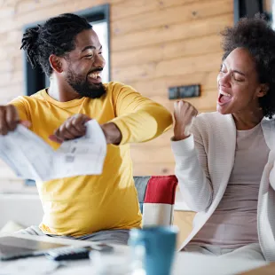 Man and women celebrating as man tears up a credit card bill