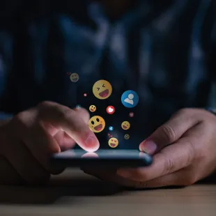 hands holding smart phone with reaction bubbles.