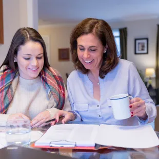 mom and daughter sitting at a table looking at paperwork