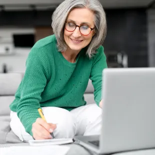 Senior woman wearing a green sweater on her laptop.