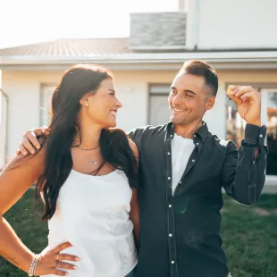 A happy couple holding keys to a home