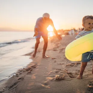 young boy running on the beach with an innertube float