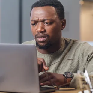 man looking worried at his laptop computer screen
