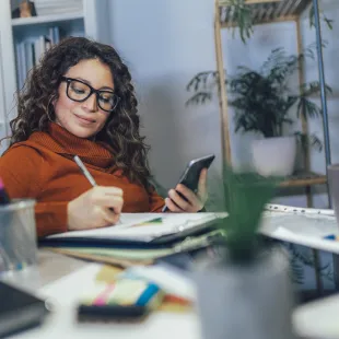 woman wearing glasses writing down her budget.