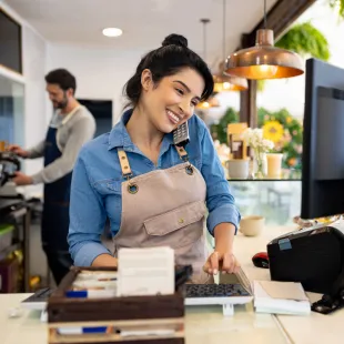 woman on the phone looking at a computer screen smiling