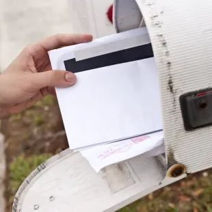a hand grabbing a letter out of a mailbox