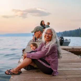senior woman sitting on a dock by the water with her family
