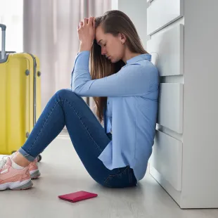 girl leaning on her hands beside her yellow suitcase.