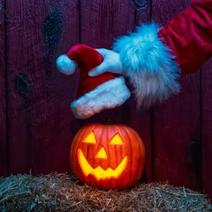 Santa putting his hat on a pumpkin