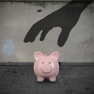 pink piggy bank with a shadow hand over it