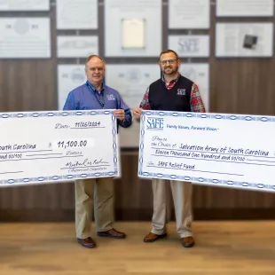 from left to right: Keith Troup, Alan Lewis, Michael Baker, Drew Huckeba holding donation checks to Salvation Army and United Way
