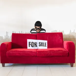 scammer standing behind a red couch that's for sale.