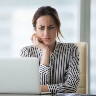 woman looking at a lap top puzzled. 
